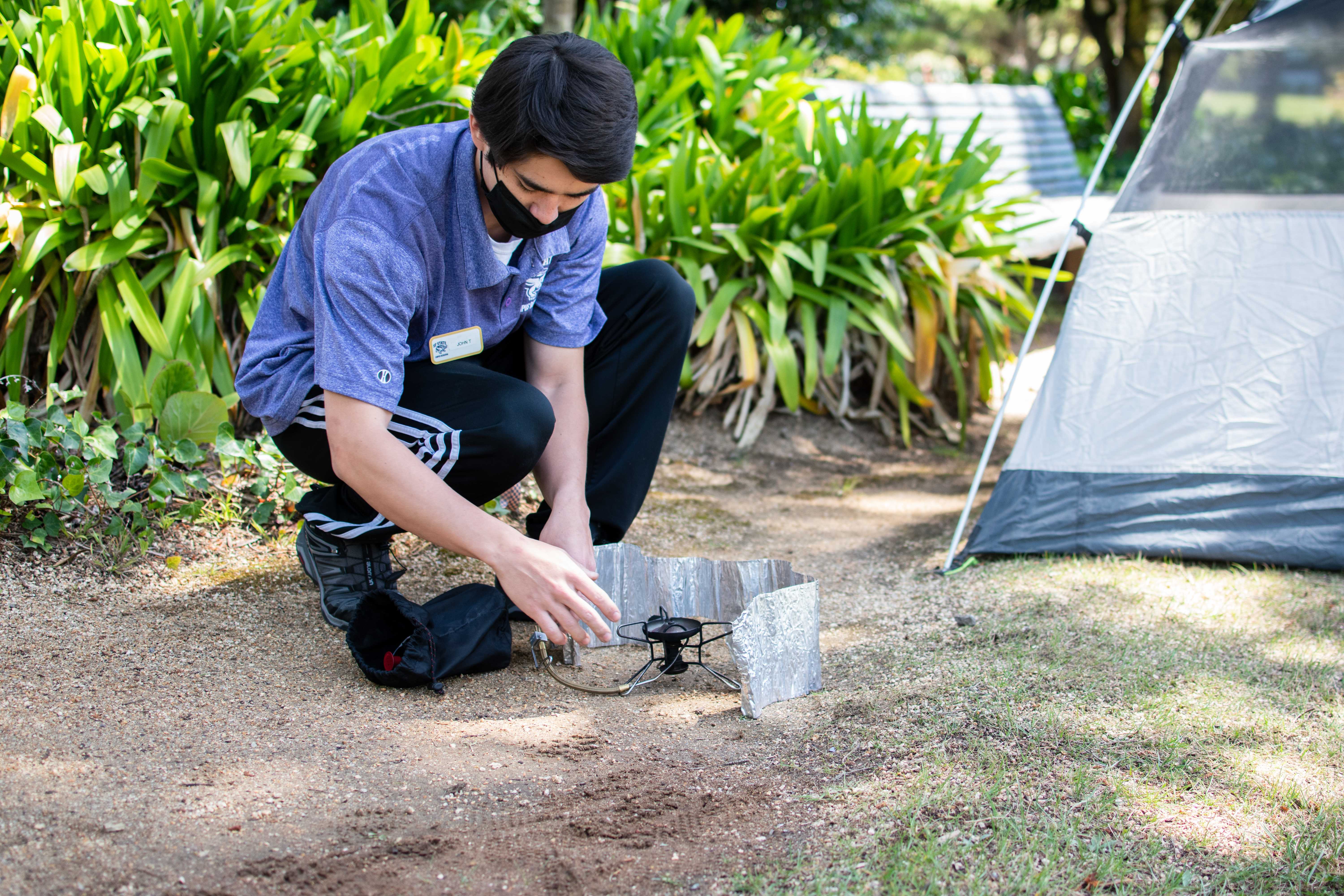 Student preparing a camp stove on the ground